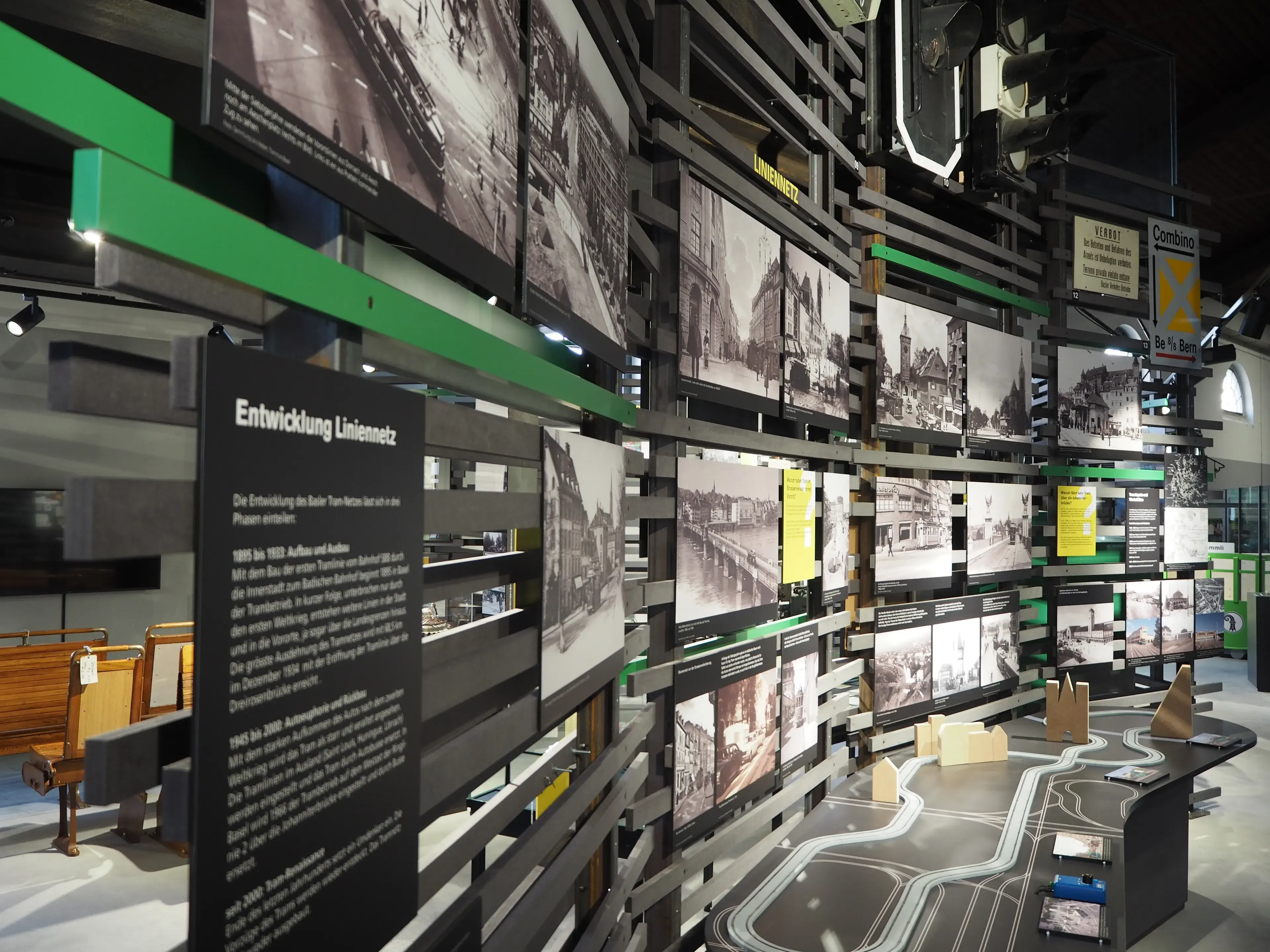 Innenansicht Tram-Museum Basel. An einer Wand hängen historische Bilder der Verkehrswege in Basel. Davor steht ein vereinfachtes Stadtmodell mit einer Tram-Linie.