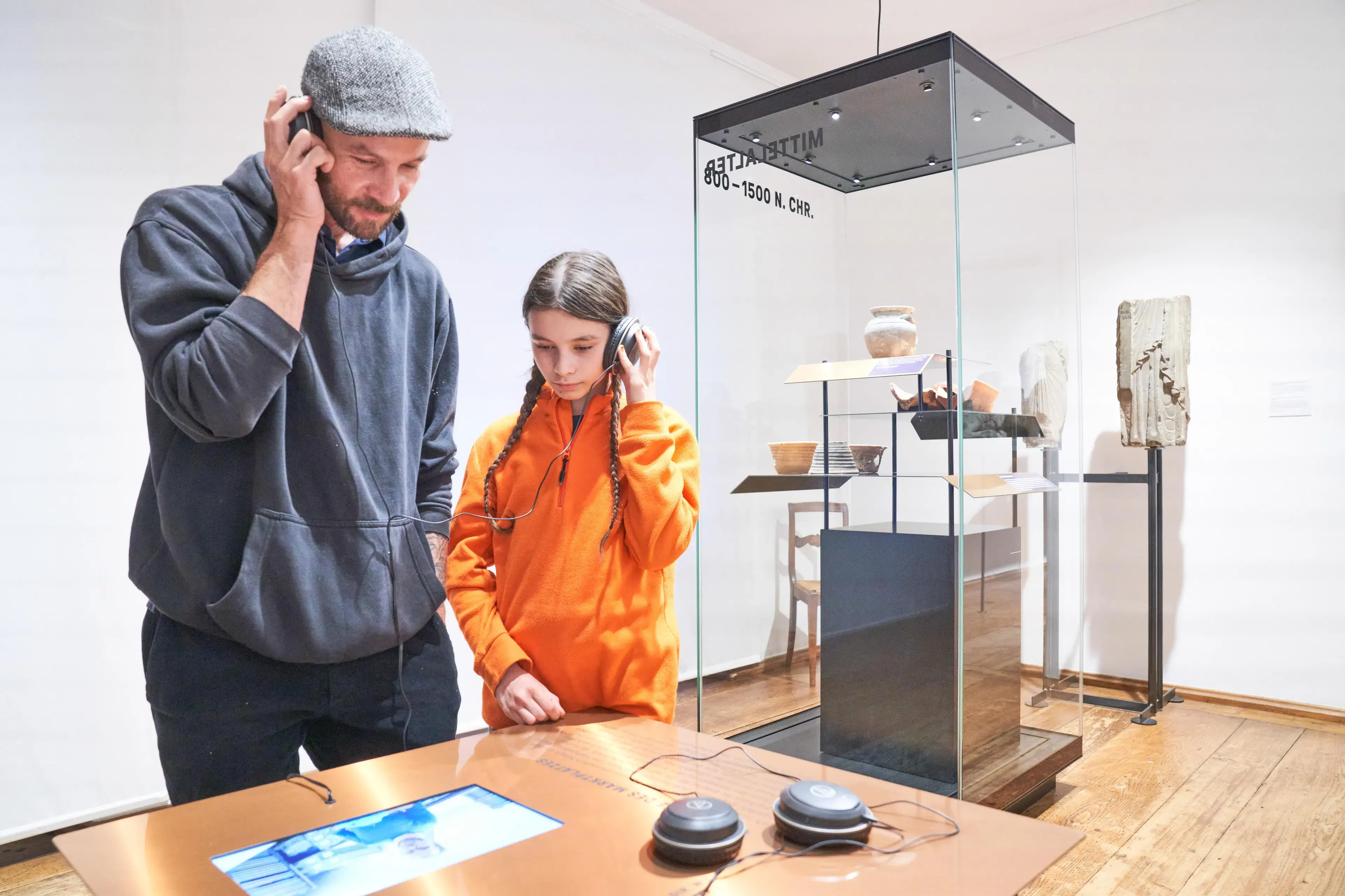 Vater und Tochter hören Audiostorys in Ausstellungsraum